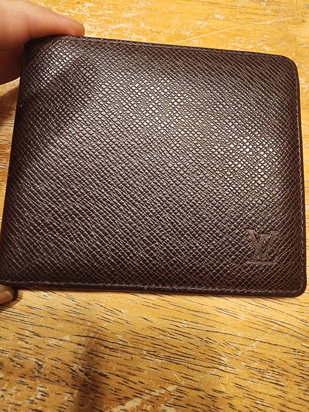 burgandy Louis Vuitton Taiga leather bifold wallet featuring a debossed LV